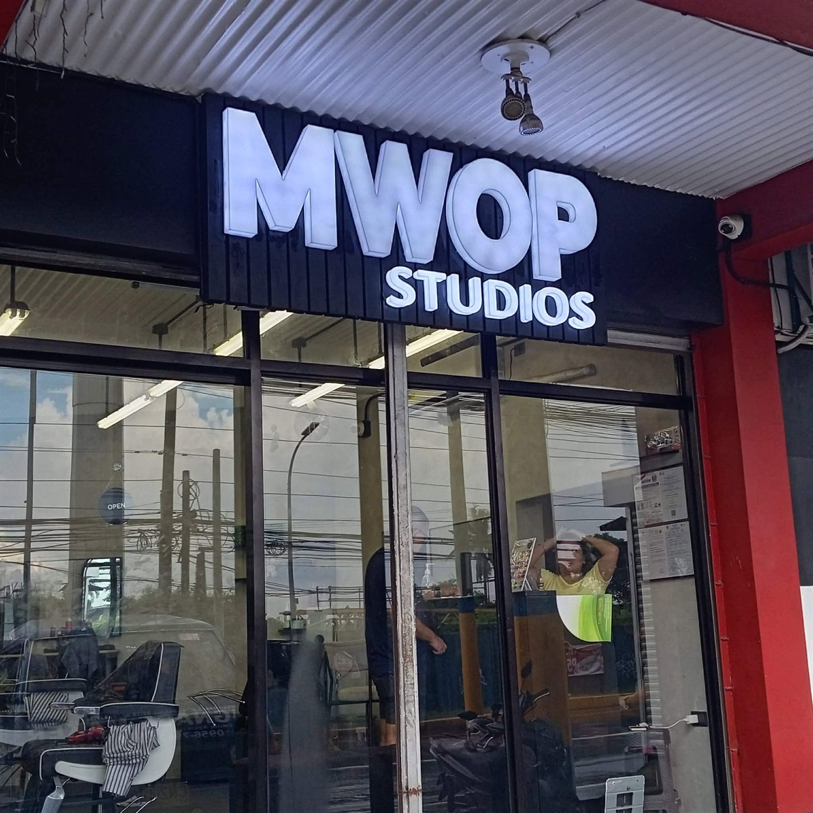 White back-lit acrylic letters spelling MWOP Studios above a glass storefront, made by Signstar