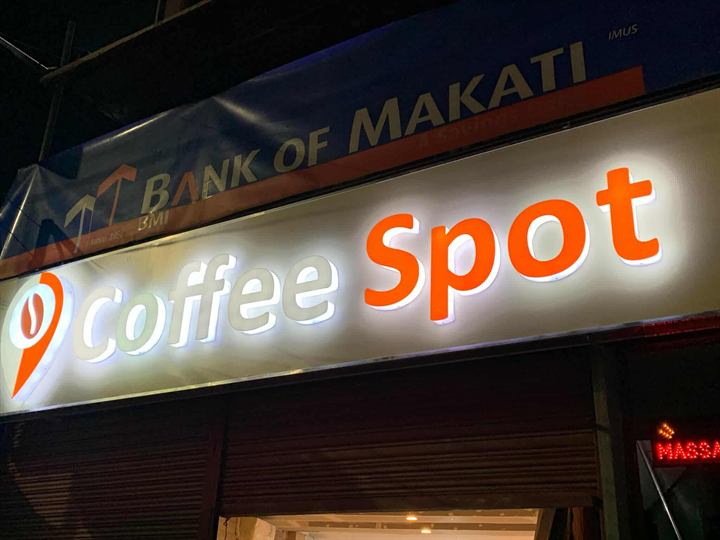 Coffee Spot warm-lit acrylic sign on a storefront
